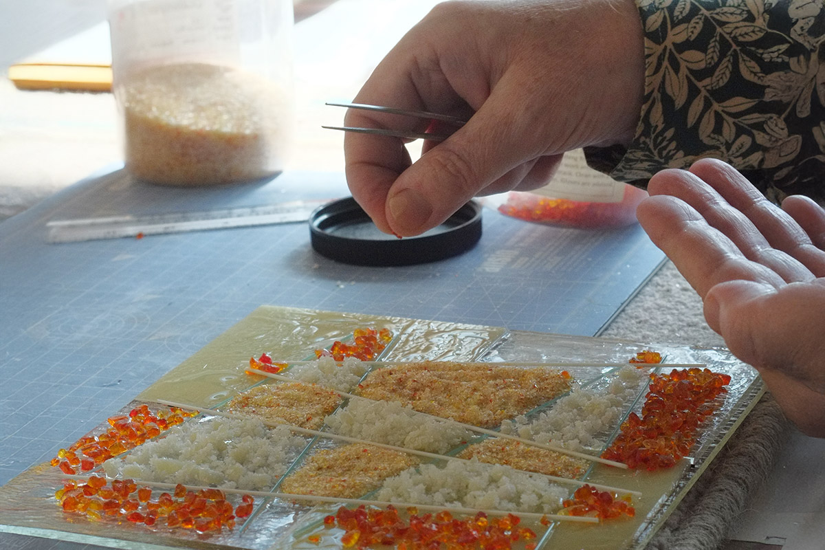 A student using glass accessories to decorate a fused glass panel