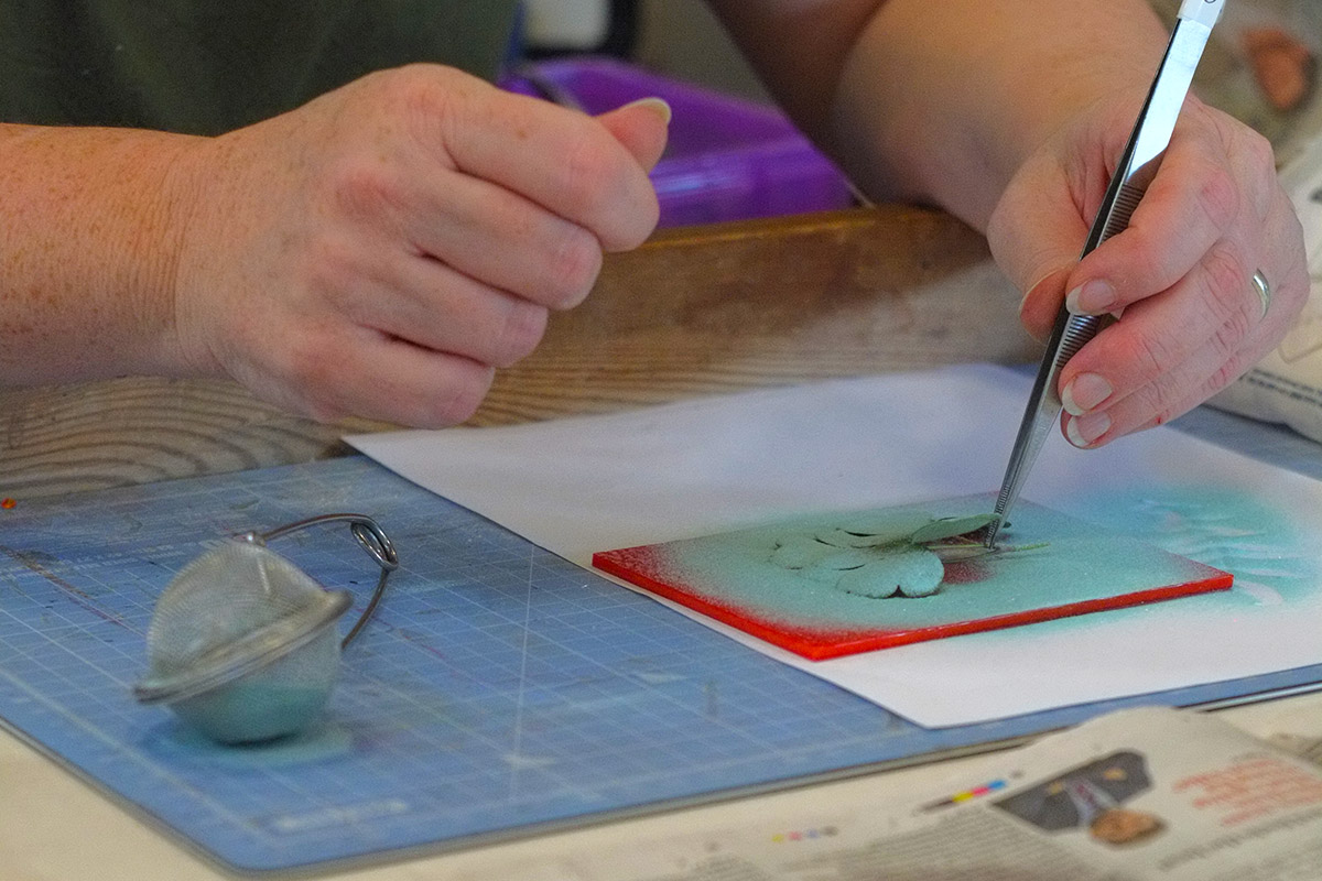 Student stencilling fused glass with glass powder